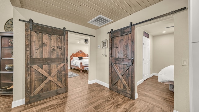 hall with wood ceiling, wood-type flooring, and a barn door