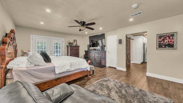 bedroom featuring ceiling fan, a barn door, hardwood / wood-style flooring, access to exterior, and stainless steel refrigerator