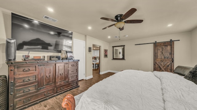 bedroom featuring ceiling fan, dark hardwood / wood-style flooring, and a barn door