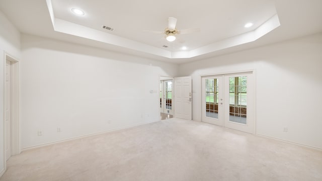 carpeted empty room with french doors, ceiling fan, and a tray ceiling