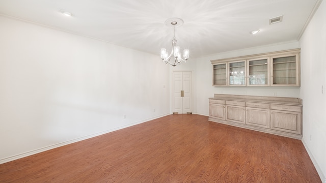 unfurnished dining area featuring ornamental molding, light hardwood / wood-style flooring, and an inviting chandelier