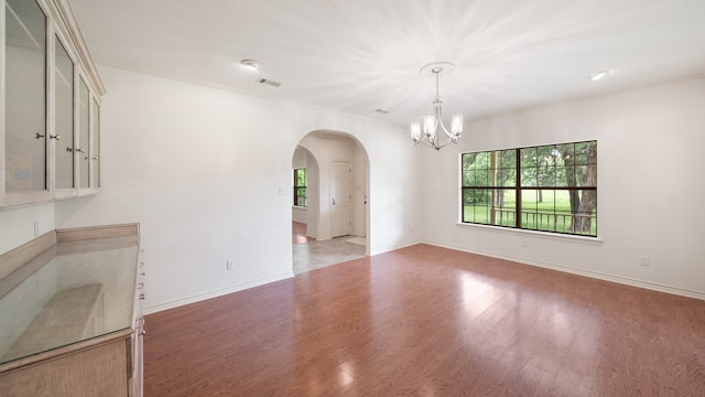 unfurnished dining area featuring a chandelier, crown molding, and hardwood / wood-style flooring