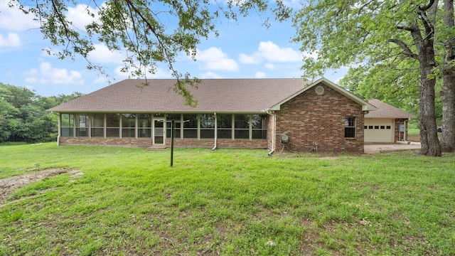 back of property featuring a yard, a garage, and a sunroom