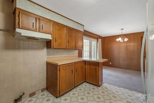 kitchen featuring kitchen peninsula, french doors, decorative light fixtures, and wooden walls