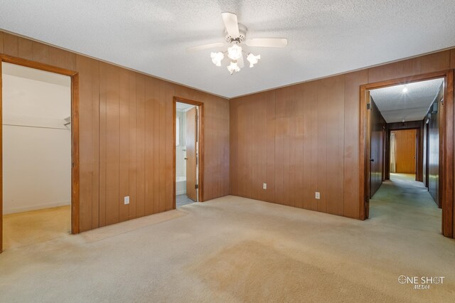 unfurnished bedroom featuring ensuite bath, a spacious closet, ceiling fan, light colored carpet, and a closet