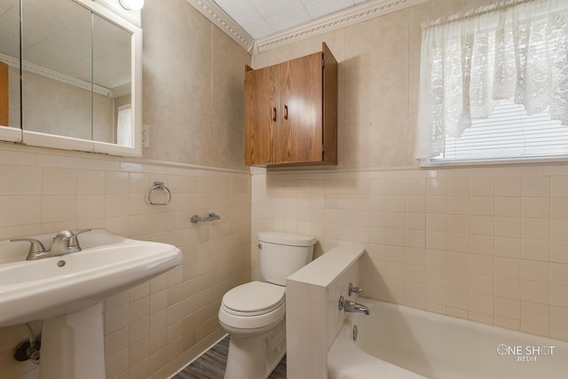 bathroom with a tub to relax in, toilet, ornamental molding, and tile walls