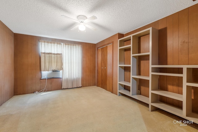 unfurnished bedroom with wooden walls, a closet, ceiling fan, and light colored carpet