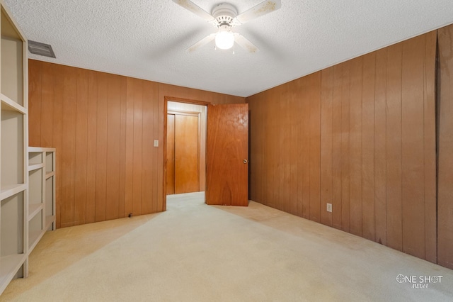 spare room with wood walls and light colored carpet