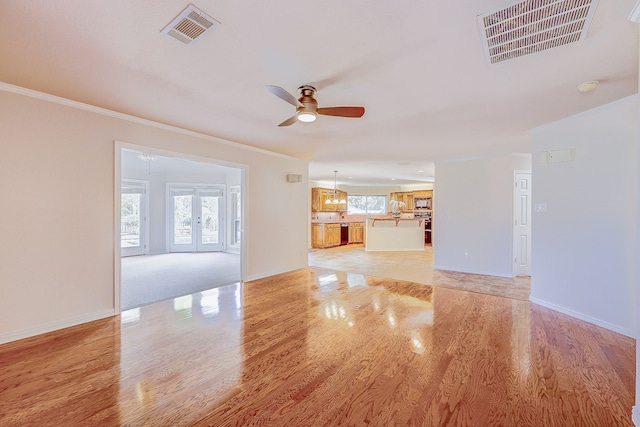 unfurnished living room with light wood-type flooring, french doors, ceiling fan, and crown molding