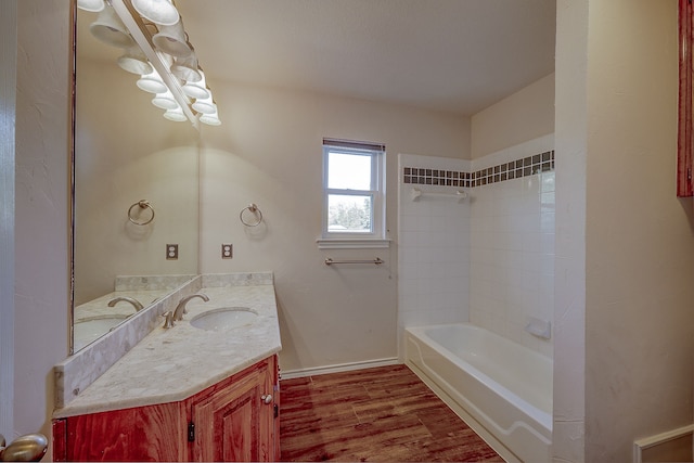 bathroom with hardwood / wood-style flooring, vanity, and tiled shower / bath combo