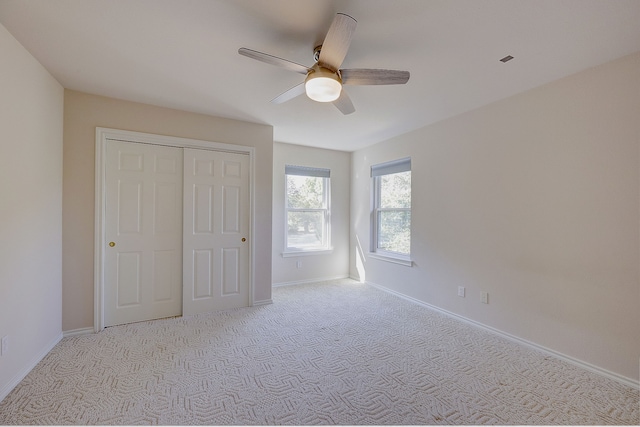 unfurnished bedroom with a closet, light colored carpet, and ceiling fan