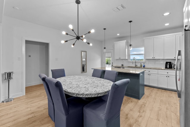 dining room with light hardwood / wood-style floors, a notable chandelier, and sink