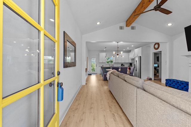 living room with lofted ceiling with beams, ceiling fan with notable chandelier, and light wood-type flooring