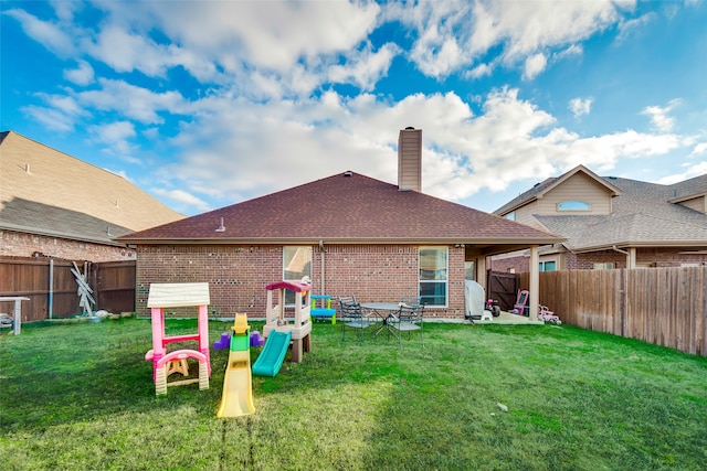 rear view of property featuring a patio, a playground, and a yard