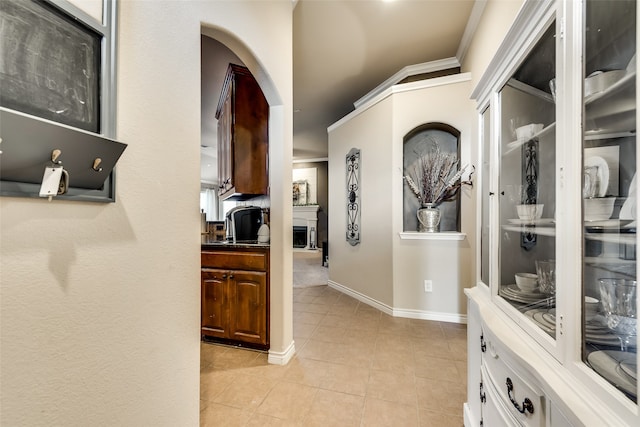 hallway featuring ornamental molding and light tile patterned floors