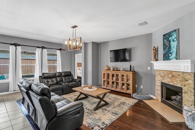 living room with a textured ceiling, light hardwood / wood-style flooring, a chandelier, and a fireplace