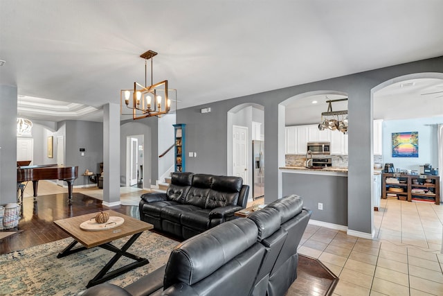 living room featuring light hardwood / wood-style flooring and ceiling fan with notable chandelier