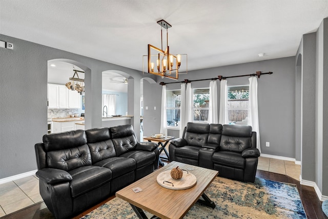 living room with a textured ceiling, sink, ceiling fan with notable chandelier, and light wood-type flooring