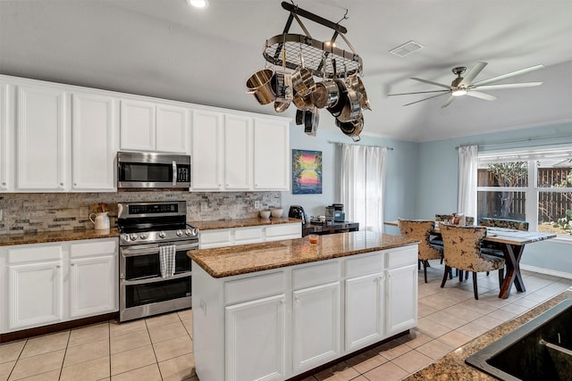 kitchen featuring stainless steel appliances, dark stone countertops, a center island, light tile patterned flooring, and white cabinets