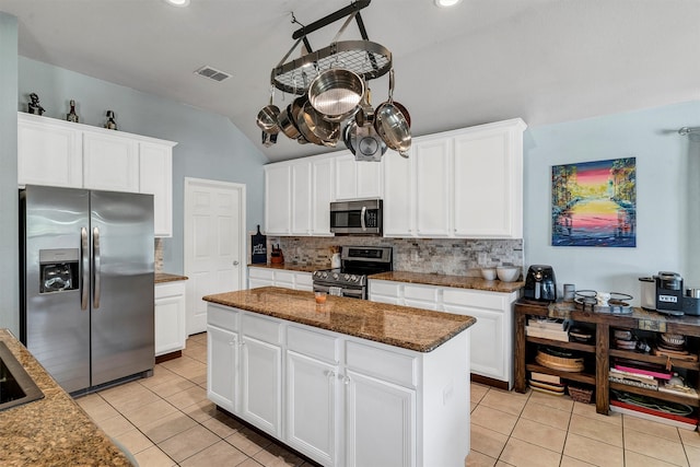 kitchen featuring white cabinetry, stainless steel appliances, a center island, and dark stone counters