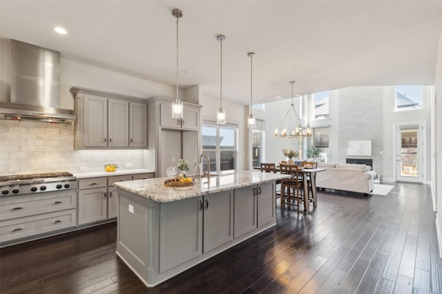 kitchen featuring a kitchen island with sink, gray cabinetry, stainless steel appliances, a kitchen breakfast bar, and ventilation hood