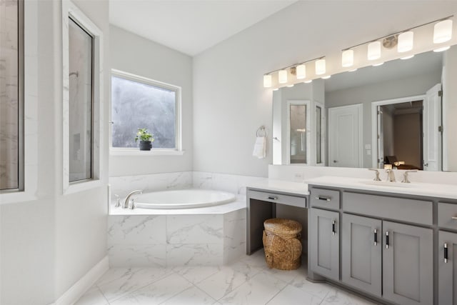 bathroom with vanity and tiled tub