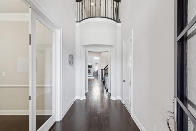 hall featuring ornamental molding, a towering ceiling, and dark hardwood / wood-style flooring