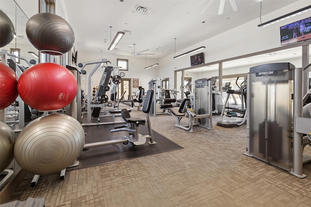 exercise room with a towering ceiling, ceiling fan, and carpet flooring