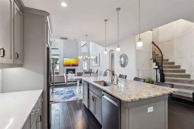 kitchen with sink, gray cabinets, a center island with sink, dark hardwood / wood-style flooring, and stainless steel dishwasher