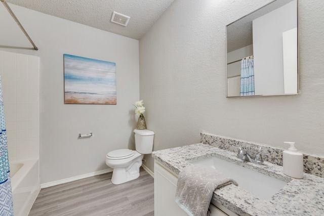 full bathroom with shower / tub combo, a textured ceiling, toilet, vanity, and hardwood / wood-style flooring