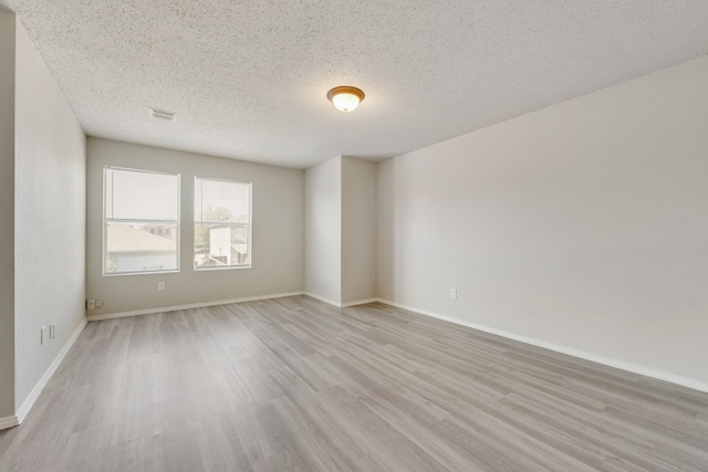 spare room with light hardwood / wood-style floors and a textured ceiling