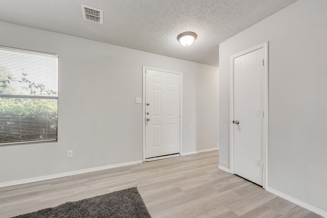 foyer entrance featuring light hardwood / wood-style flooring and a textured ceiling