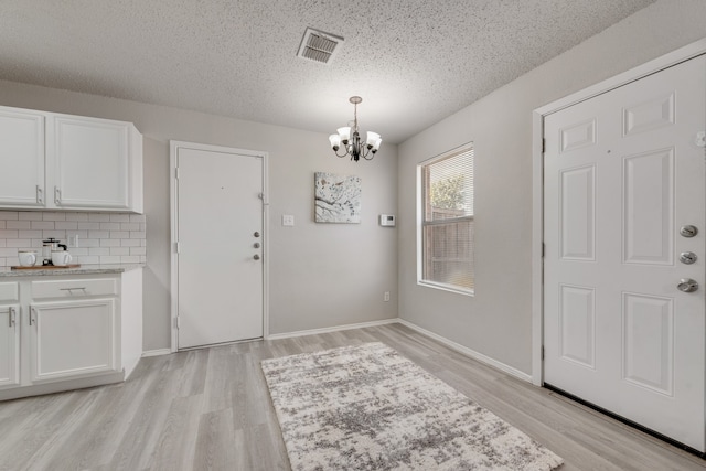 interior space with a chandelier, a textured ceiling, and light hardwood / wood-style floors