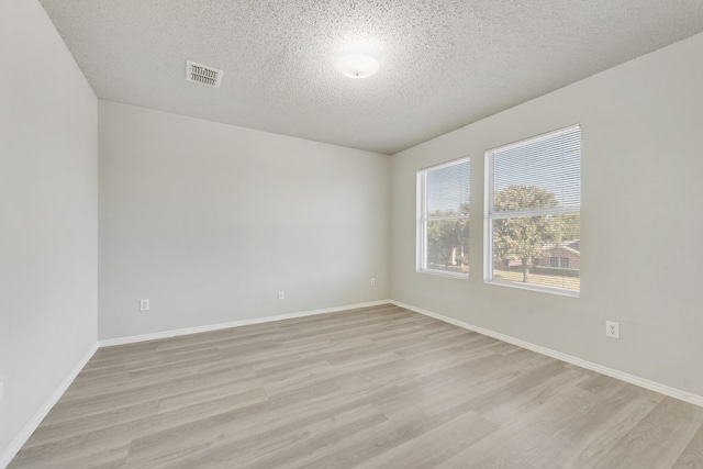 unfurnished room with a textured ceiling and light wood-type flooring