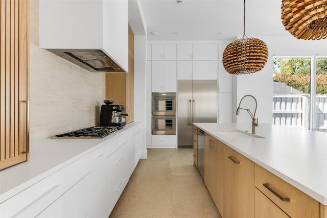 kitchen featuring white cabinets, hanging light fixtures, sink, range hood, and stainless steel appliances