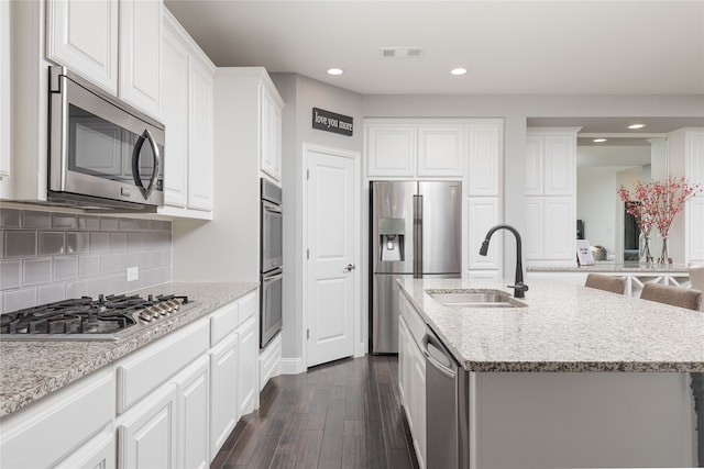 kitchen featuring white cabinetry, stainless steel appliances, a center island with sink, and dark hardwood / wood-style flooring