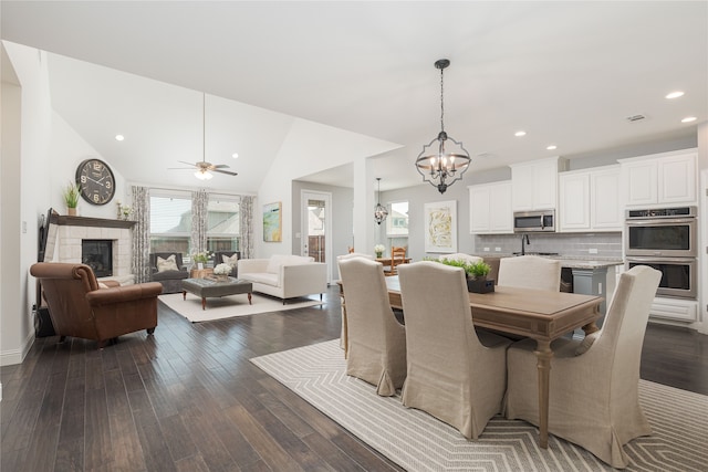 dining space featuring sink, vaulted ceiling, a fireplace, and dark hardwood / wood-style floors