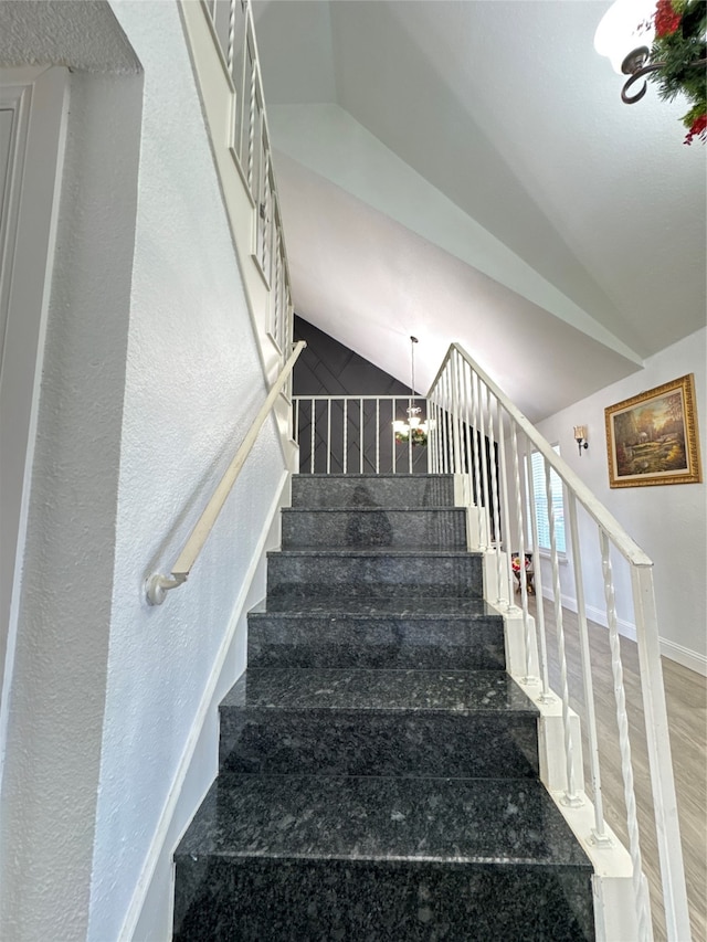 stairs featuring a chandelier, wood-type flooring, and vaulted ceiling