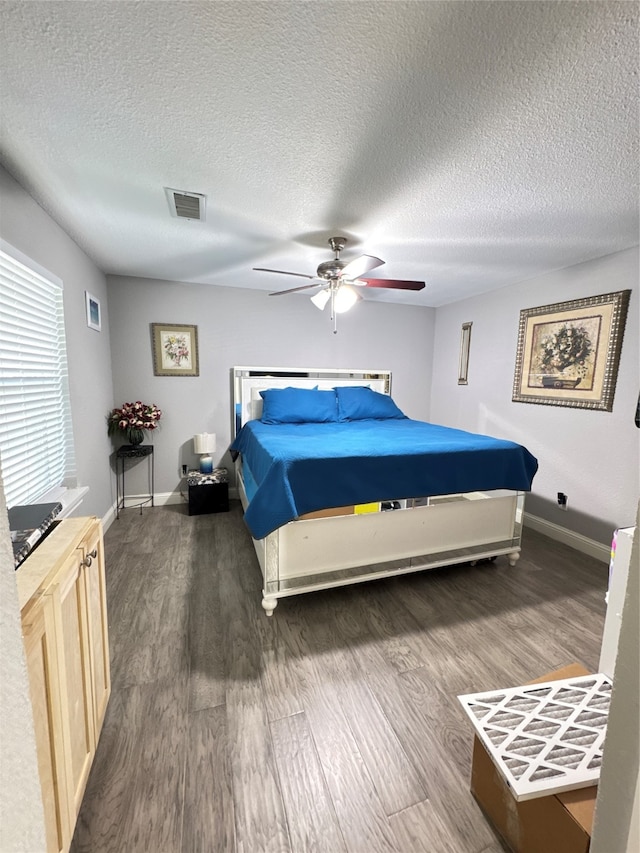 bedroom with ceiling fan, dark wood-type flooring, and a textured ceiling