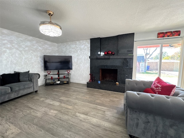 living room featuring wood-type flooring, a textured ceiling, and a high end fireplace