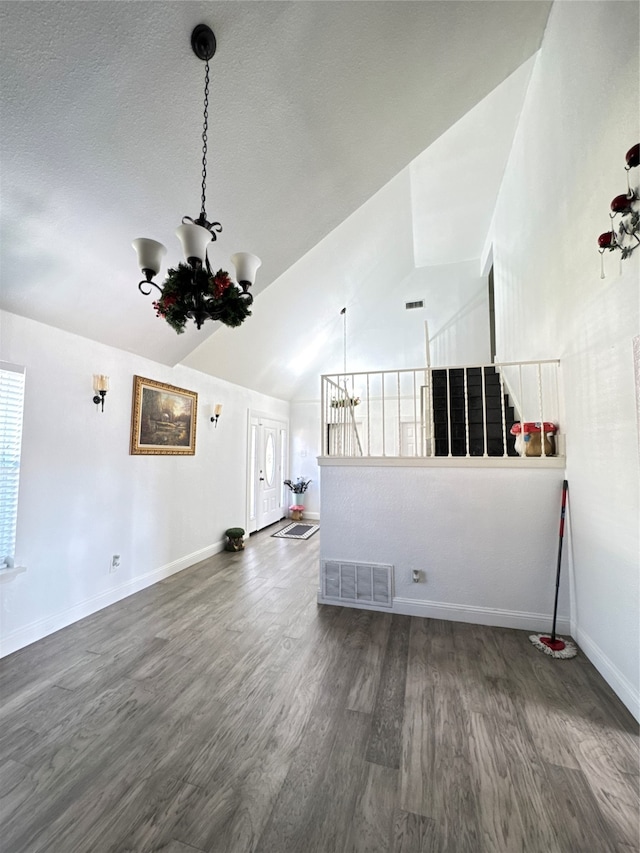 spare room with dark hardwood / wood-style floors, high vaulted ceiling, and a chandelier