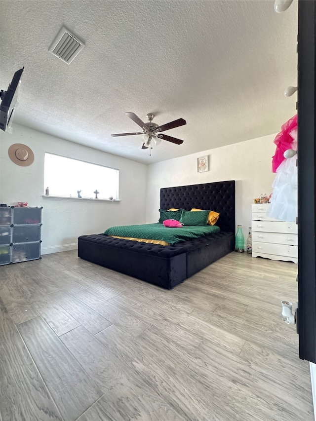 bedroom featuring ceiling fan, light hardwood / wood-style flooring, and a textured ceiling