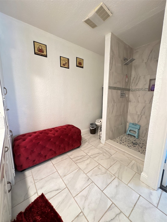 bathroom featuring a textured ceiling and tiled shower