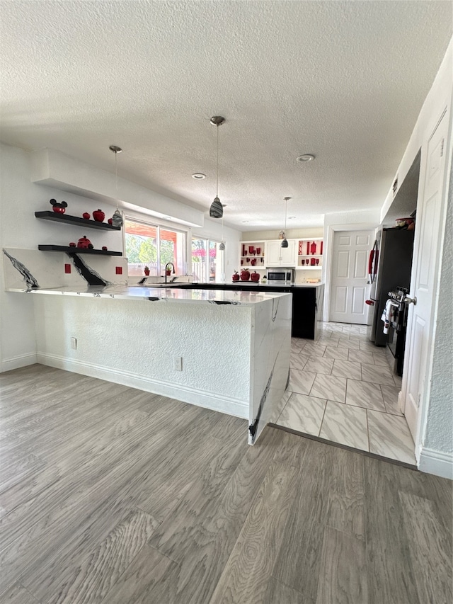 kitchen featuring pendant lighting, a textured ceiling, and light wood-type flooring