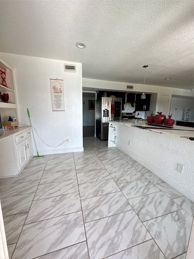 kitchen with a textured ceiling, built in shelves, pendant lighting, and stainless steel refrigerator with ice dispenser