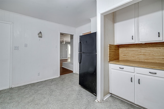 kitchen featuring white cabinetry, crown molding, and black refrigerator