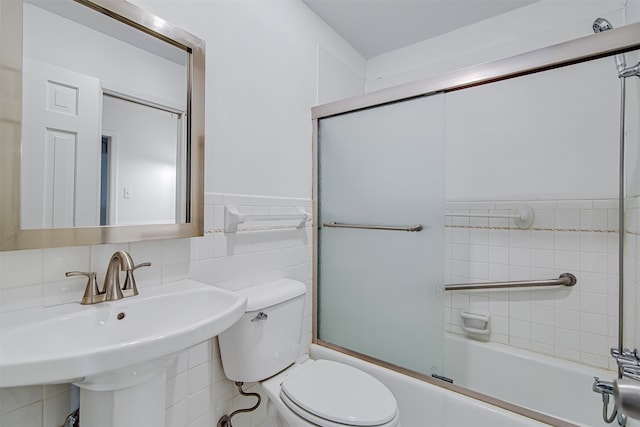 full bathroom with tile walls, sink, shower / bath combination with glass door, and toilet