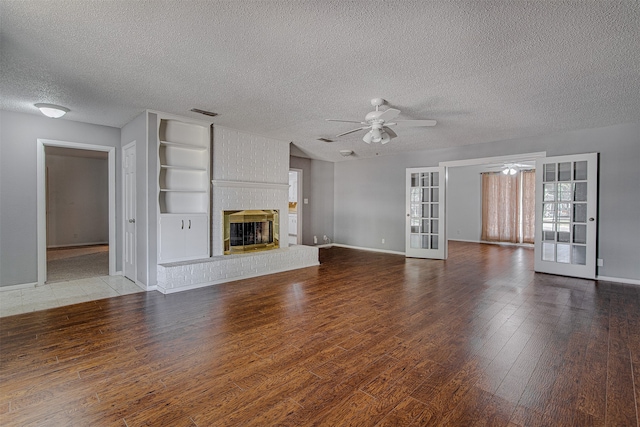 unfurnished living room with french doors, hardwood / wood-style floors, a textured ceiling, a fireplace, and ceiling fan