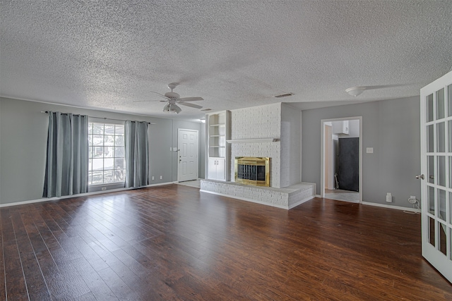 unfurnished living room featuring ceiling fan, a fireplace, a textured ceiling, and dark hardwood / wood-style floors