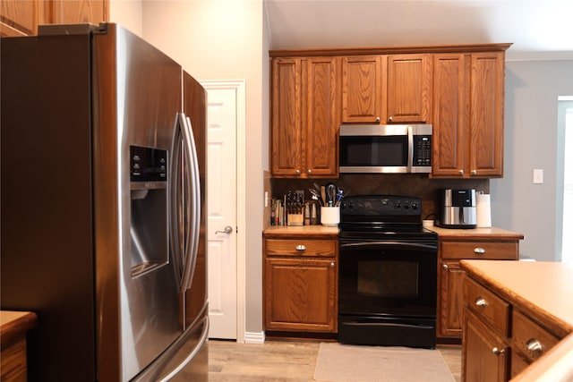 kitchen with tasteful backsplash, appliances with stainless steel finishes, and light hardwood / wood-style flooring